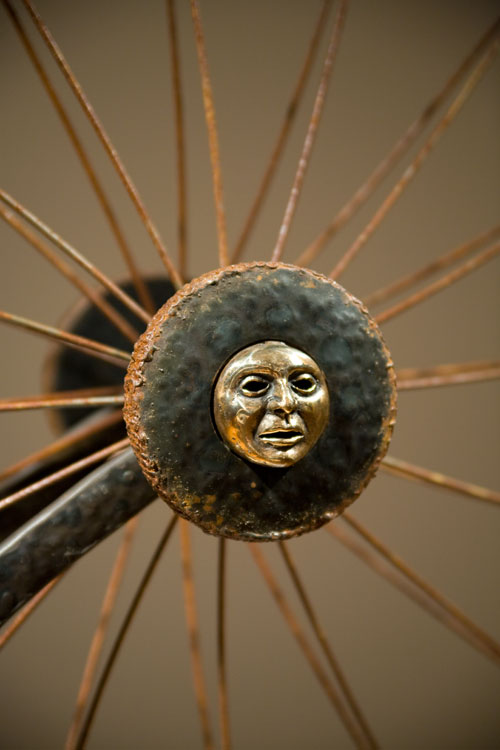 golden sculpture of a face surrounded by spokes